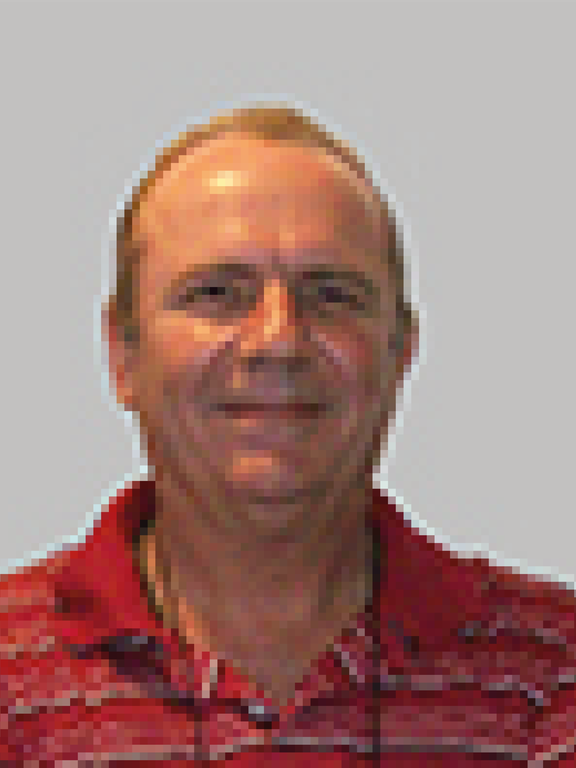 White male with short brown hair, smiling, wearing a red shirt with white and black stripes