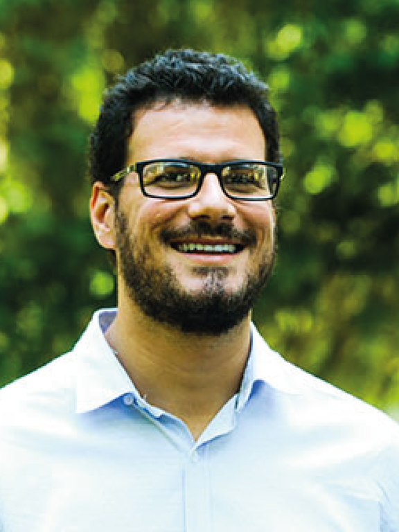 White man with short brown hair and brown beard, wearing blue glasses with rectangular frame