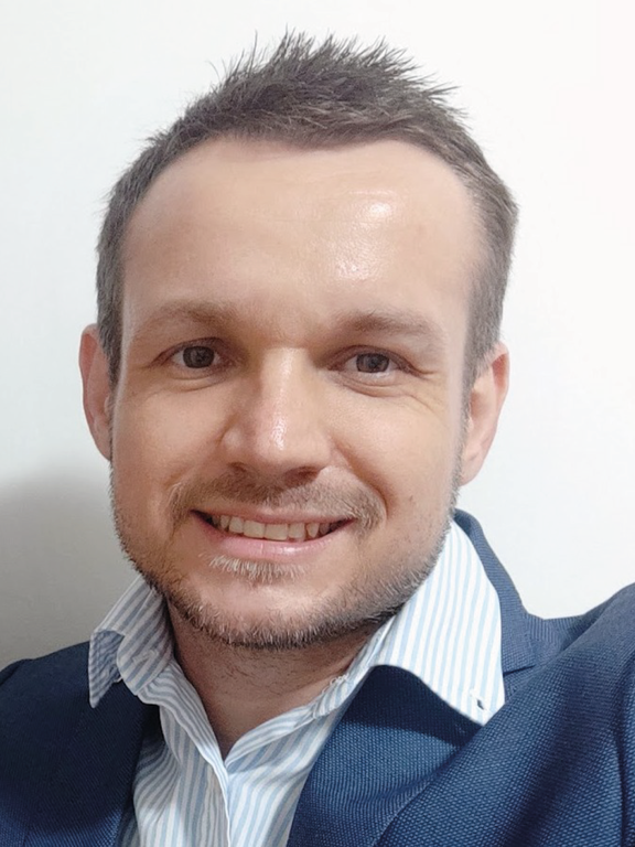 Photo of white man, blond straight hair,  without glasses, blue and white shirt and navy blue coat.