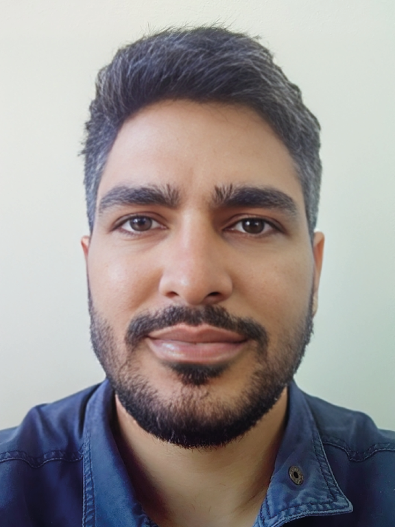 Male, brown skin, black hair, brown eyes, wearing a beard and navy blue jacket.