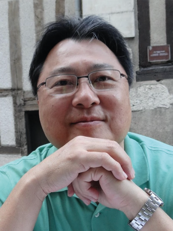 Homem, cabelo negro curto, usando óculos, camisa verde.